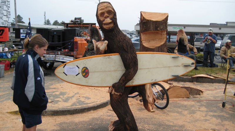 Chainsaw carving of Sasquatch with a surfboard.